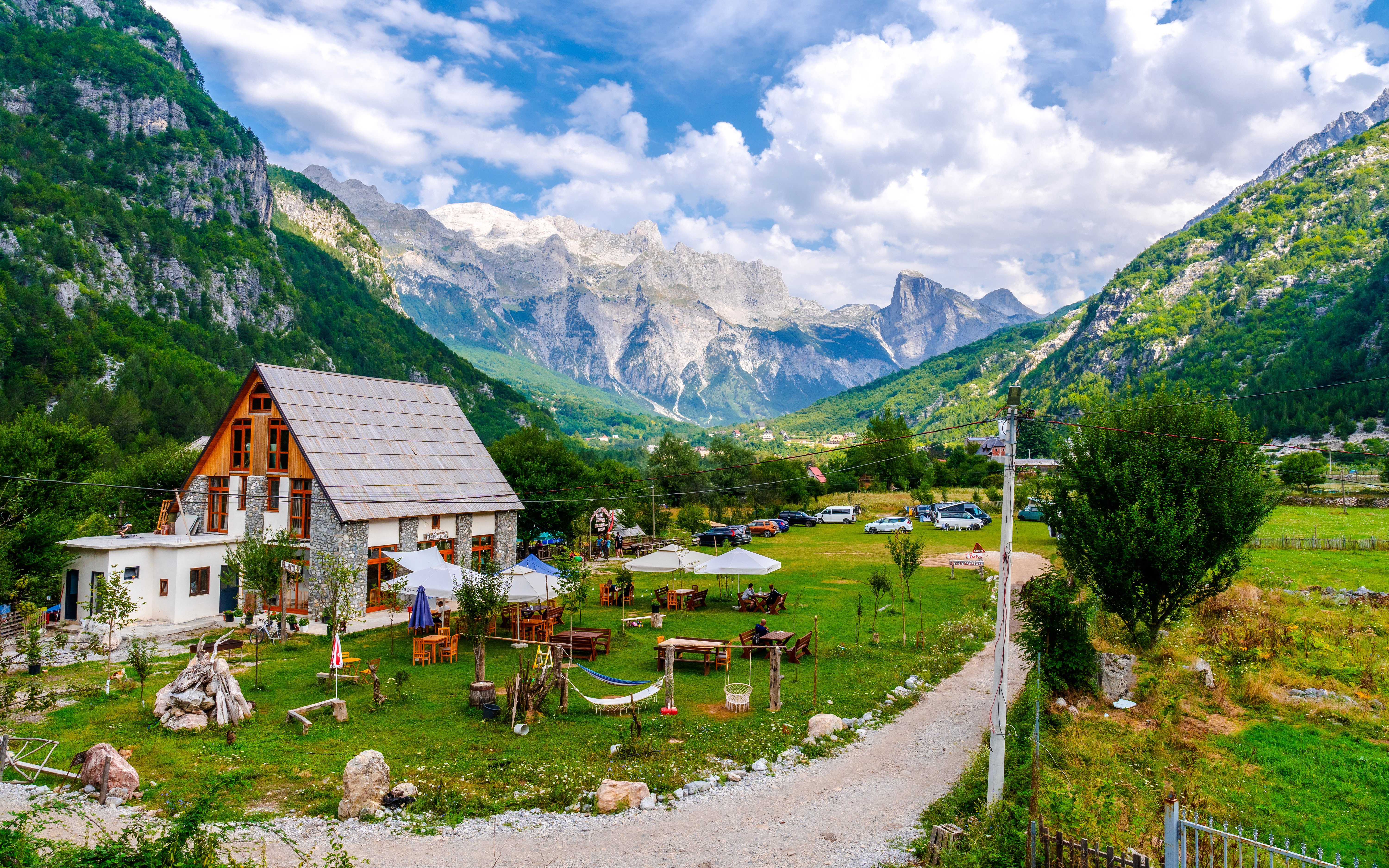 Mountain lodge and outdoor seating in Valley of Theth, Albania, with scenic mountain backdrop.