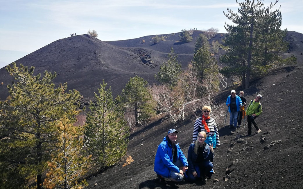 Group hiking on Mount Etna's volcanic terrain, Sicily, during a guided tour.