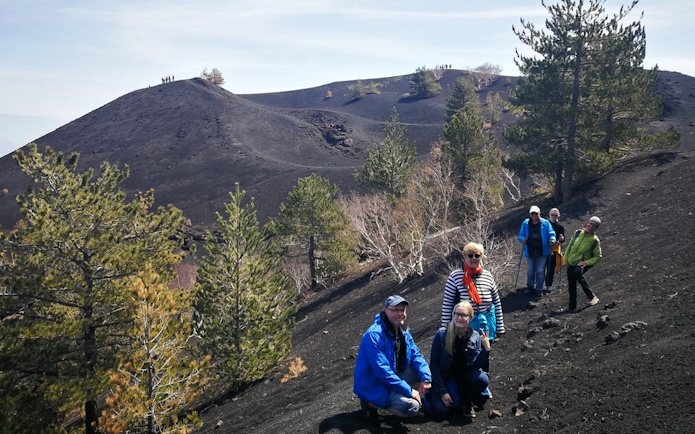 Group hiking on Mount Etna's volcanic terrain, Sicily, during a guided tour.