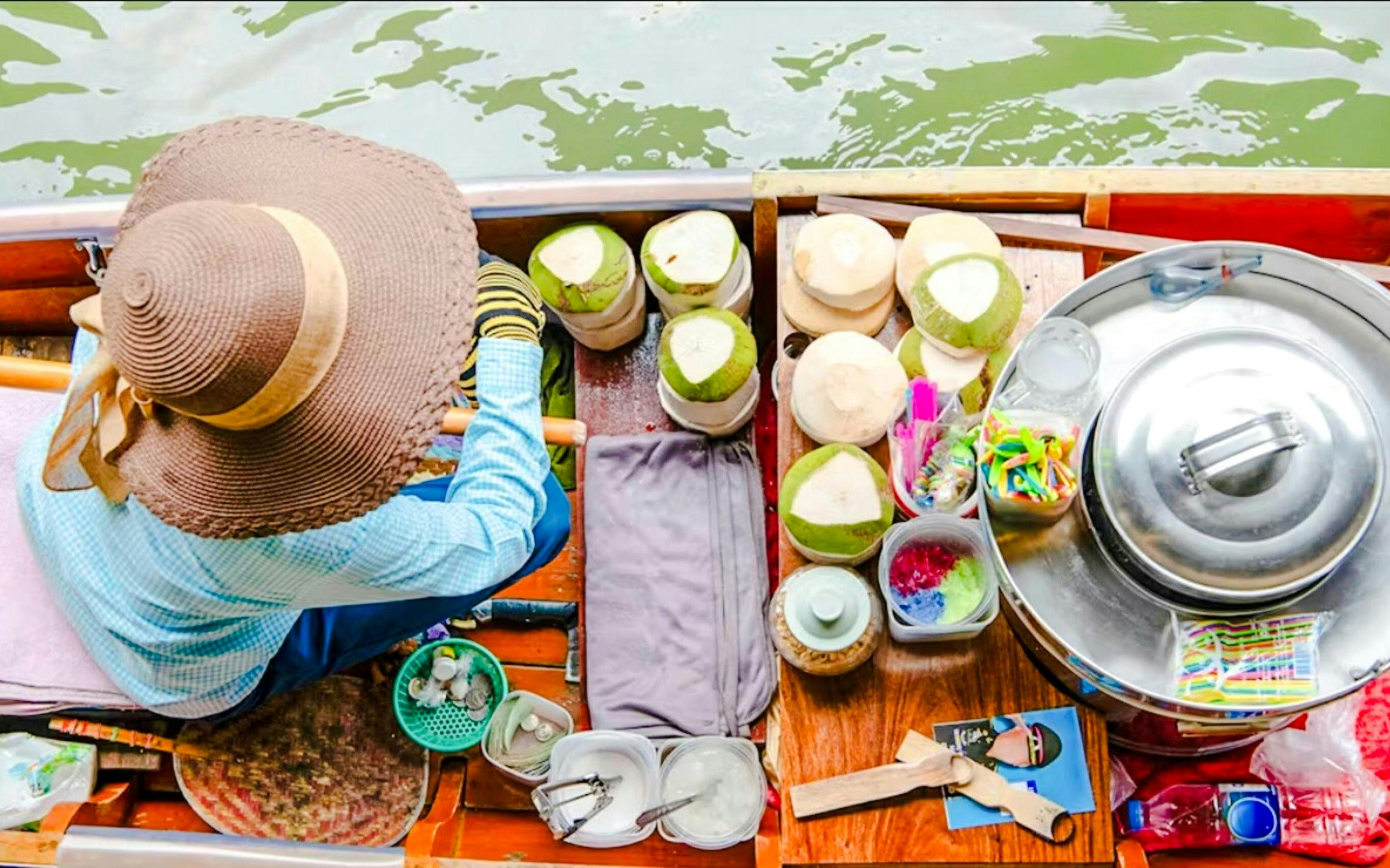 Woman selling coconuts from a boat at Damnoen Saduak Floating Market, Thailand.