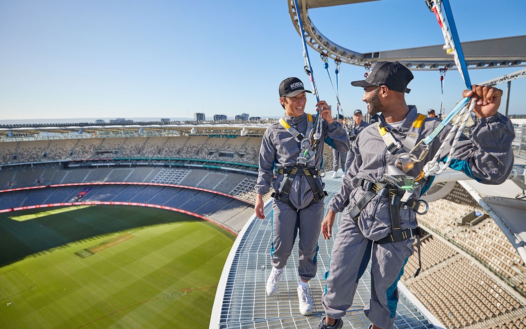 Visitors harnessed on Optus Stadium roof during Vertigo experience in Perth, Australia.