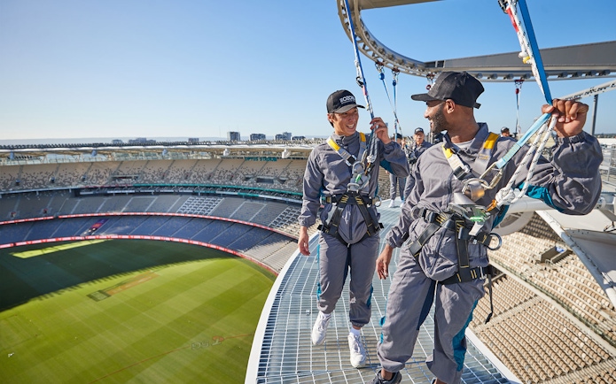 Visitors harnessed on Optus Stadium roof during Vertigo experience in Perth, Australia.