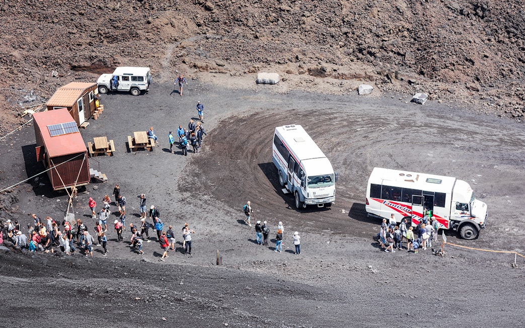 Tourists disembarking from 4x4 vehicles at Mount Etna's volcanic landscape.