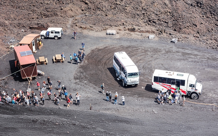 Tourists disembarking from 4x4 vehicles at Mount Etna's volcanic landscape.