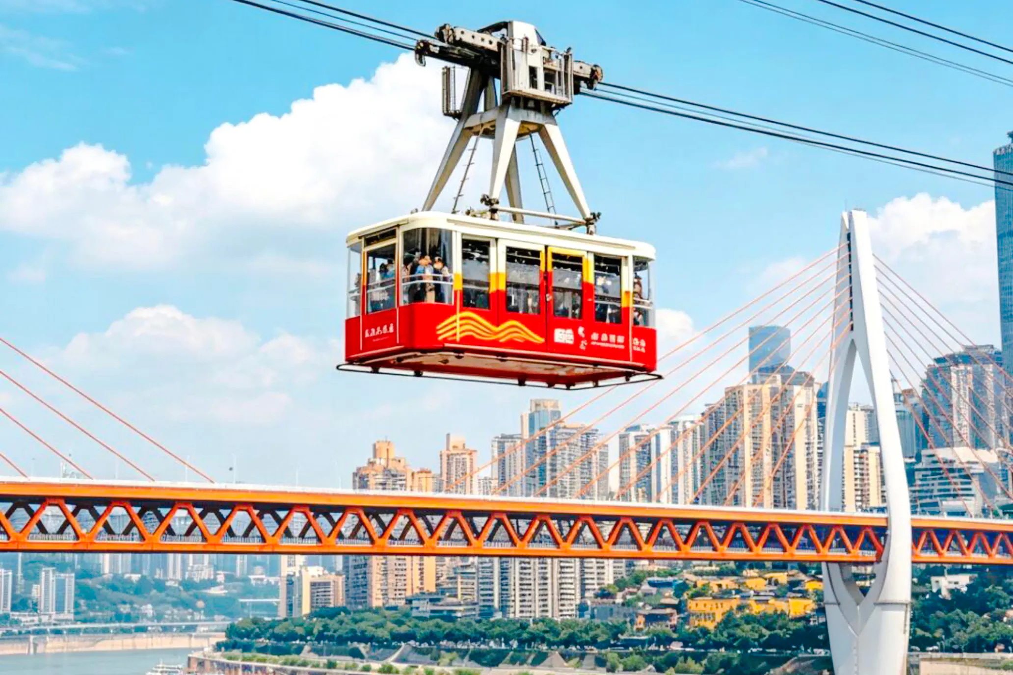 Cable car crossing over a bridge with Chongqing cityscape in the background.