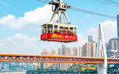 Cable car crossing over a bridge with Chongqing cityscape in the background.