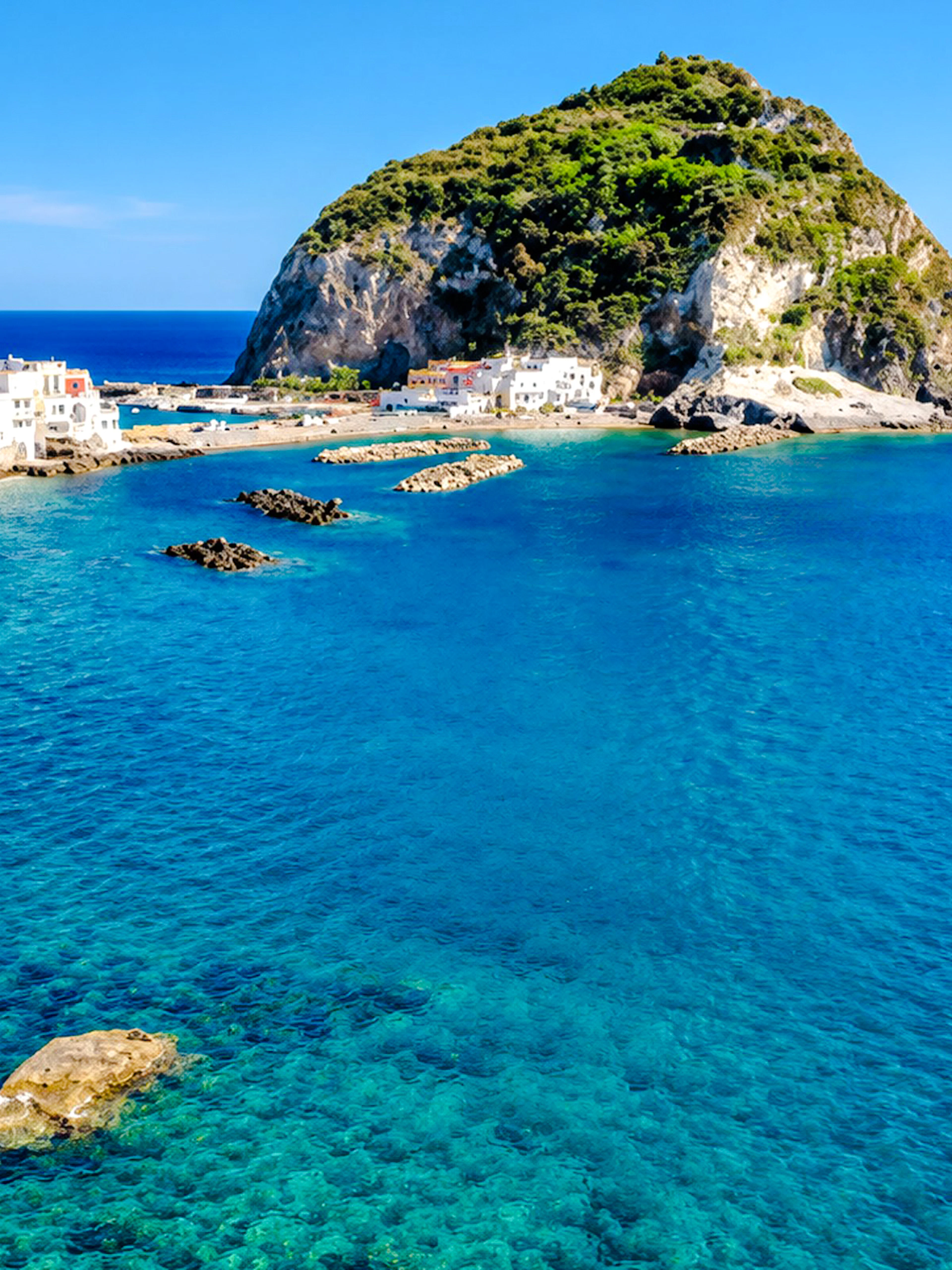 Ischia coastline with clear blue water and rocky cliffs, Naples boat tour location.