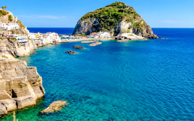 Ischia coastline with clear blue water and rocky cliffs, Naples boat tour location.