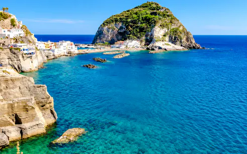 Ischia coastline with clear blue water and rocky cliffs, Naples boat tour location.