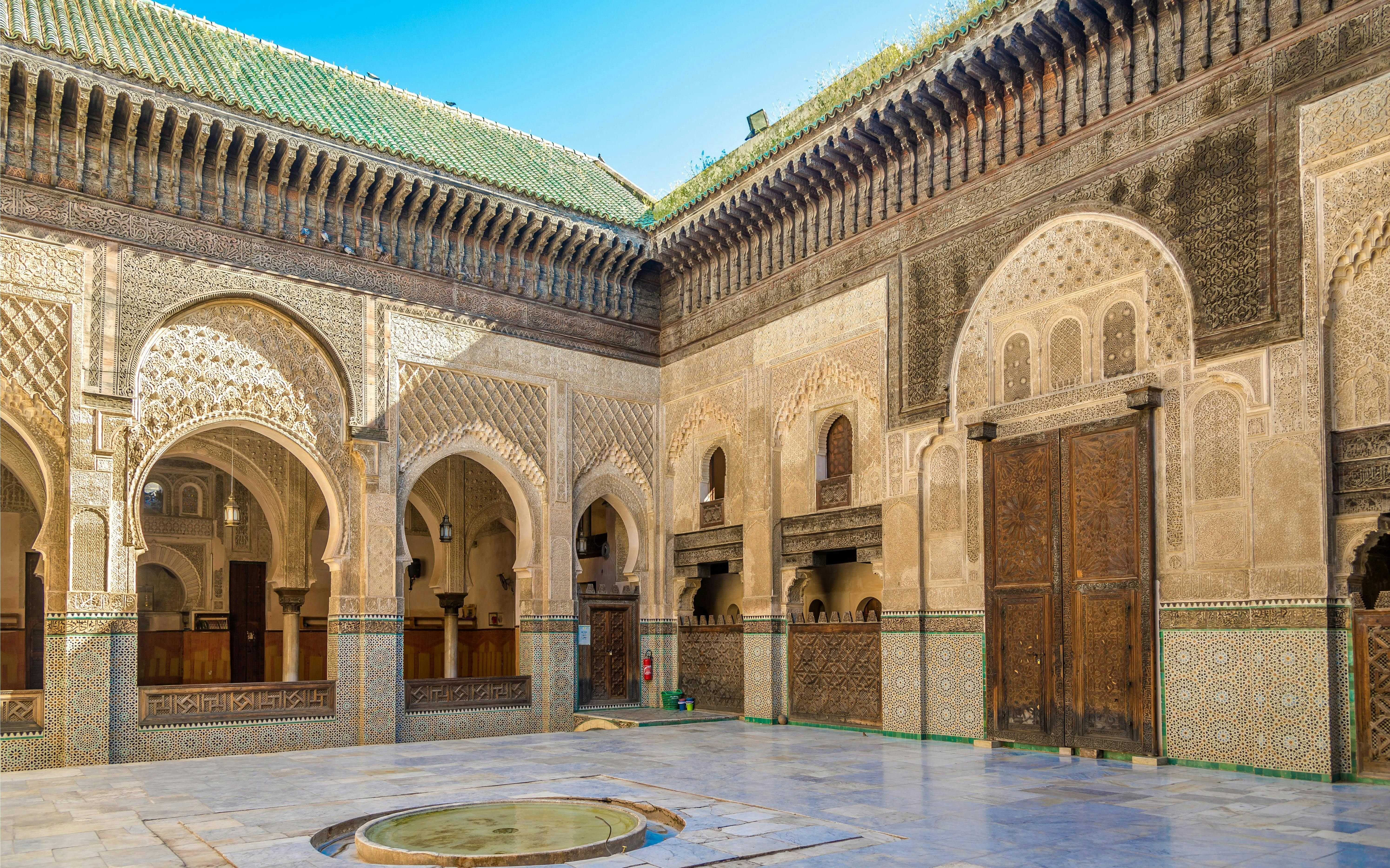 Courtyard of Bou Inania Medresa with intricate tilework and arches, Fez, Morocco.