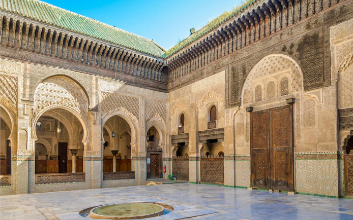 Courtyard of Bou Inania Medresa with intricate tilework and arches, Fez, Morocco.