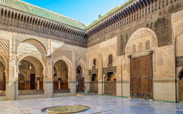 Courtyard of Bou Inania Medresa with intricate tilework and arches, Fez, Morocco.