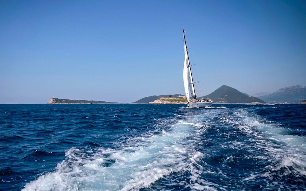 Sailboat on Adriatic Sea during Kotor Boat Tour with mountains in the background.