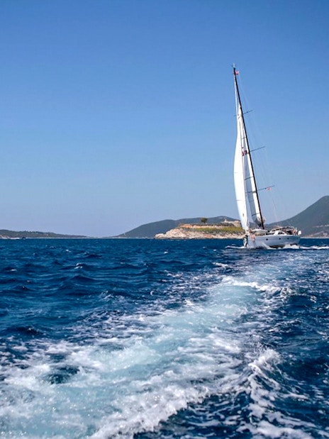 Sailboat on Adriatic Sea during Kotor Boat Tour with mountains in the background.