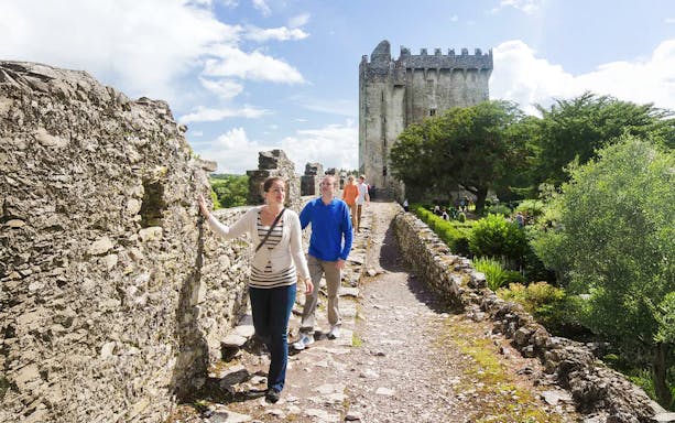 Tourists walking along the stone path at Blarney Castle, Ireland.