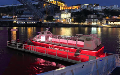 Party boat docked on the Douro River at night, Porto city lights in background.