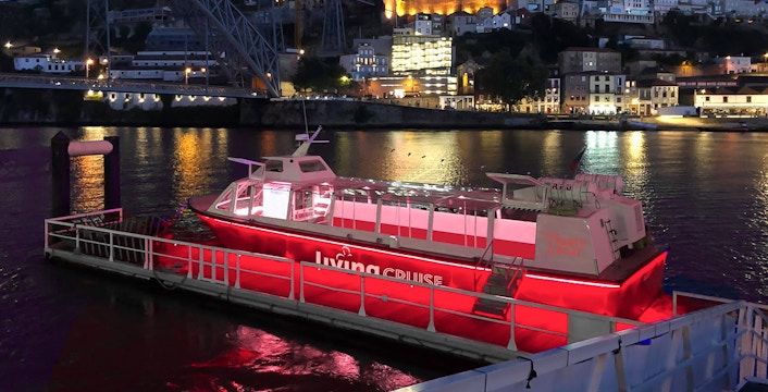 Party boat docked on the Douro River at night, Porto city lights in background.