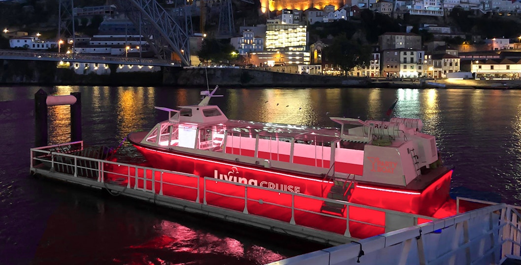 Party boat docked on the Douro River at night, Porto city lights in background.