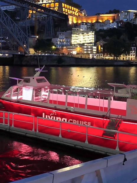 Party boat docked on the Douro River at night, Porto city lights in background.
