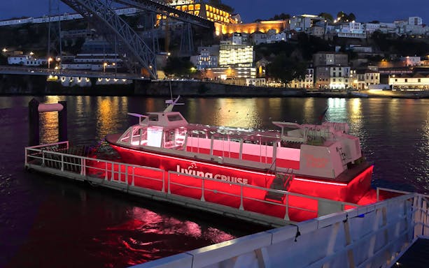 Party boat docked on the Douro River at night, Porto city lights in background.