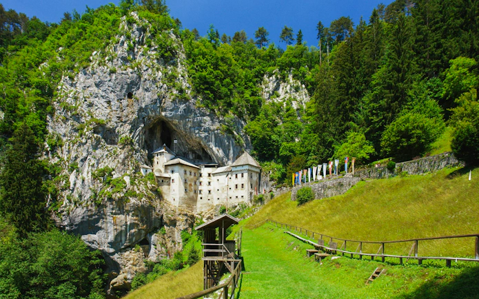 Predjama Castle nestled in a cliffside surrounded by lush greenery, Slovenia.