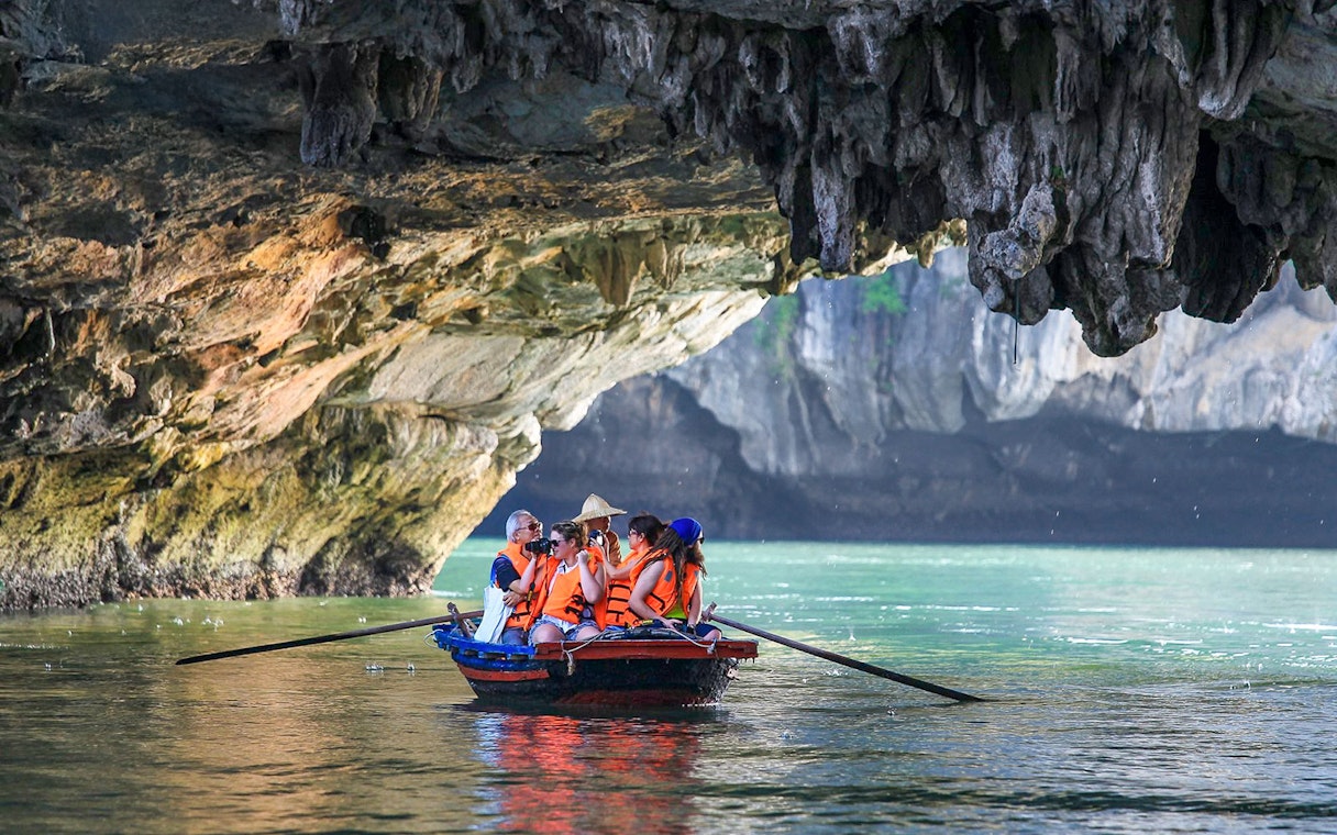 Tourists in a boat exploring a cave in Ha Long Bay, Vietnam.