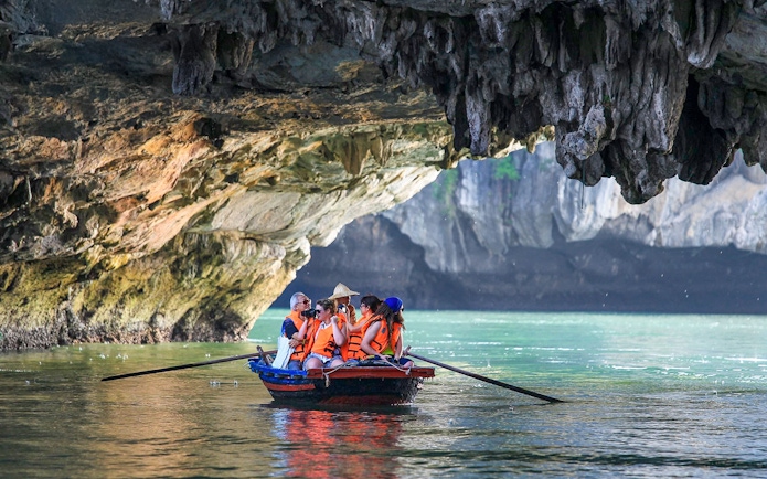 Tourists in a boat exploring a cave in Ha Long Bay, Vietnam.