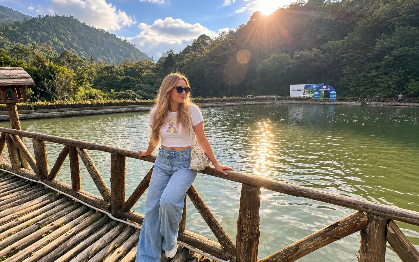 Person on a wooden bridge over a lake with mountains in Sapa, Vietnam.