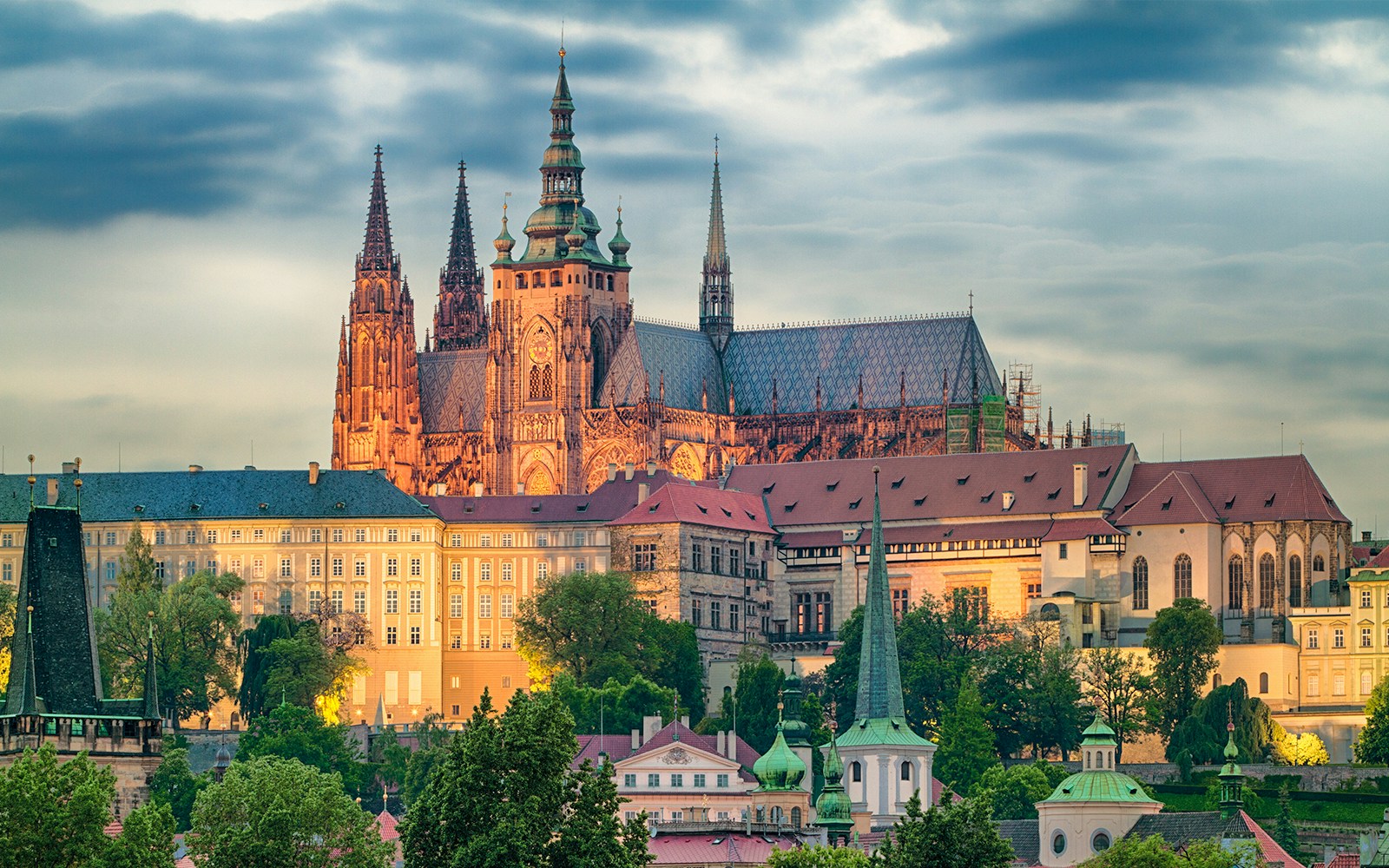 Prague Castle with Gothic spires and historic buildings at sunset.