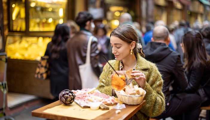 Woman enjoying gourmet street food at an outdoor cafe in Rome.