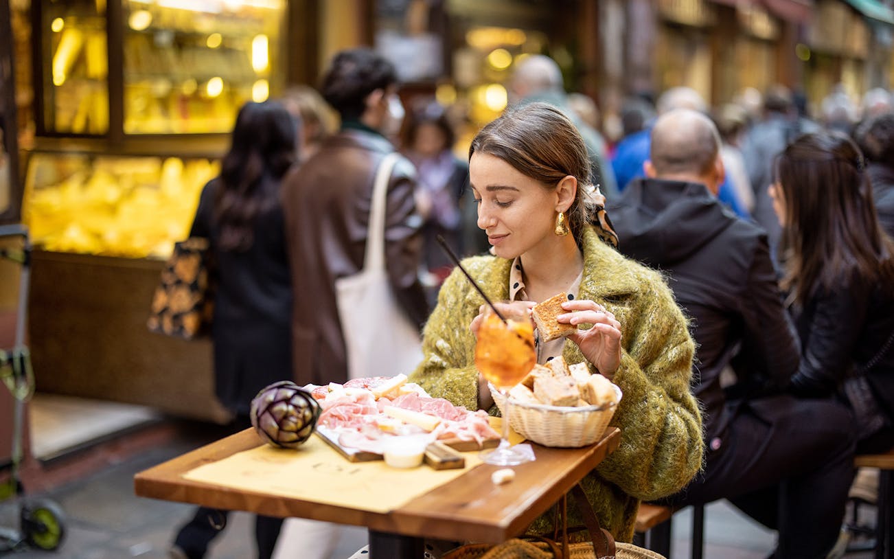 Woman enjoying gourmet street food at an outdoor cafe in Rome.