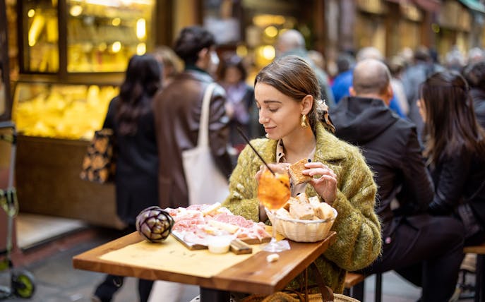 Woman enjoying gourmet street food at an outdoor cafe in Rome.