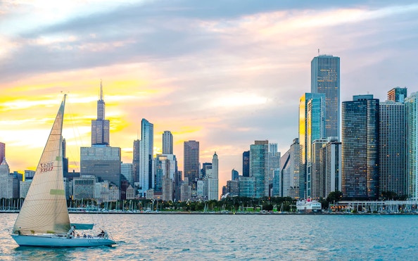 Sailboat on Lake Michigan with Chicago skyline at sunset.