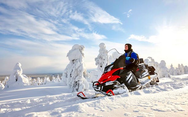 Snowmobile rider exploring snowy landscape during Rovaniemi safari adventure.