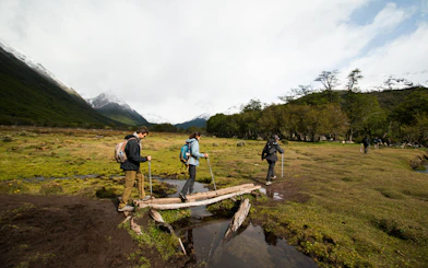 Hikers crossing a small wooden bridge during Vinciguerra Glacier trek in Ushuaia, Argentina.