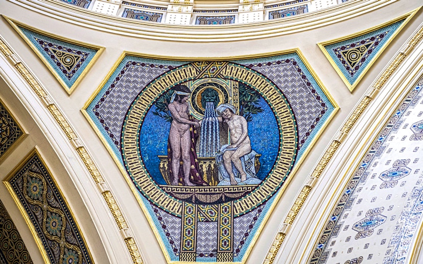 Mosaic artwork on Széchenyi Spa wall, Budapest, depicting classical figures and fountain.