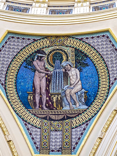 Mosaic artwork on Széchenyi Spa wall, Budapest, depicting classical figures and fountain.