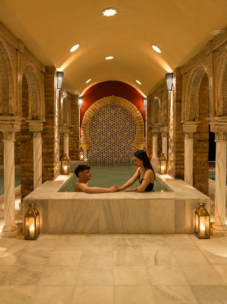 Visitors enjoying a traditional Hammam bath in Granada with ornate arches and warm lighting.