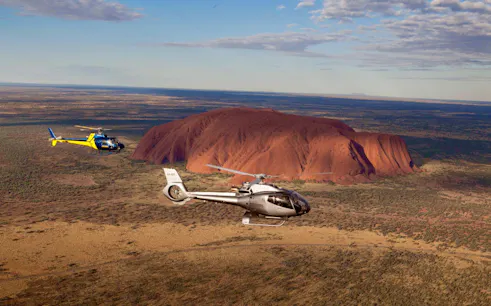 Helicopters flying over Uluru at sunset during a 36-minute tour in Australia.