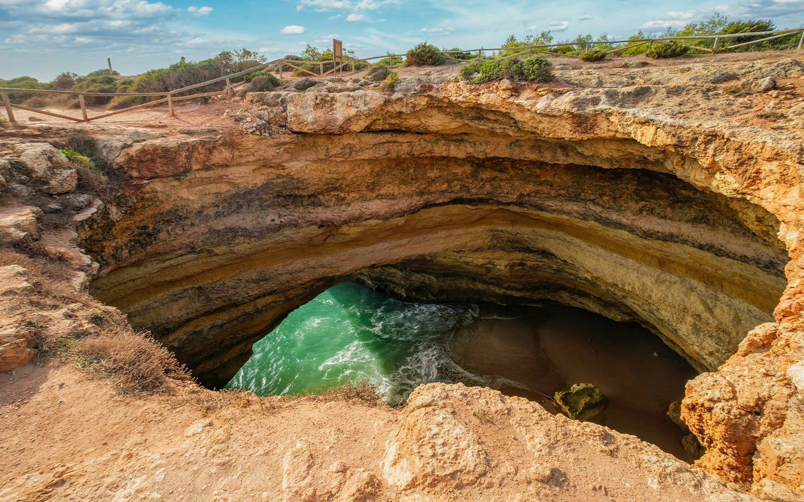 Benagil Sinkhole Viewpoint with ocean waves entering the cave in Algarve, Portugal.