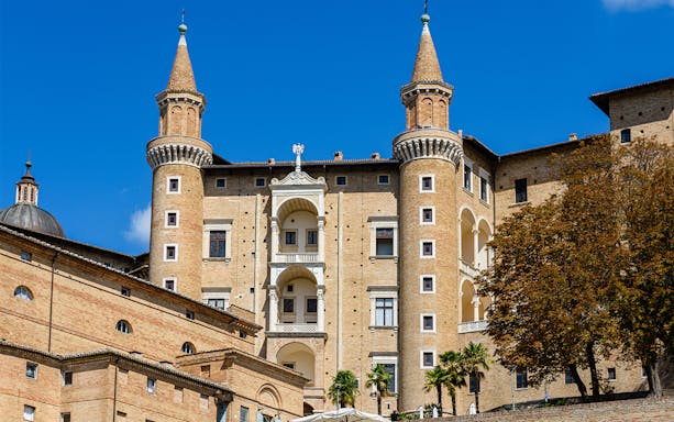 Facade of Ducal Palace in Urbino with twin towers and arched windows.