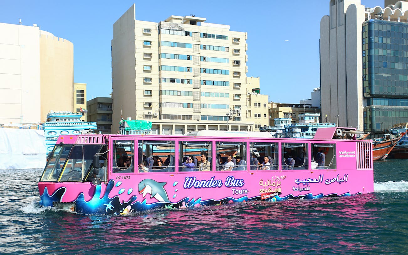Dubai Wonder Bus cruising through city waters with passengers onboard.