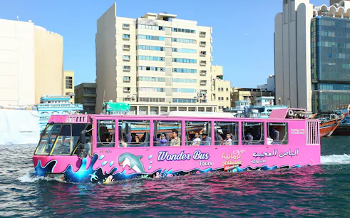 Dubai Wonder Bus cruising through city waters with passengers onboard.