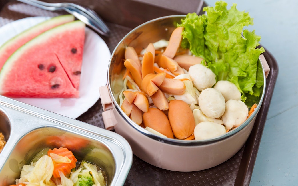 Breakfast buffet with sausages, lettuce, and watermelon slices on a beach setting.