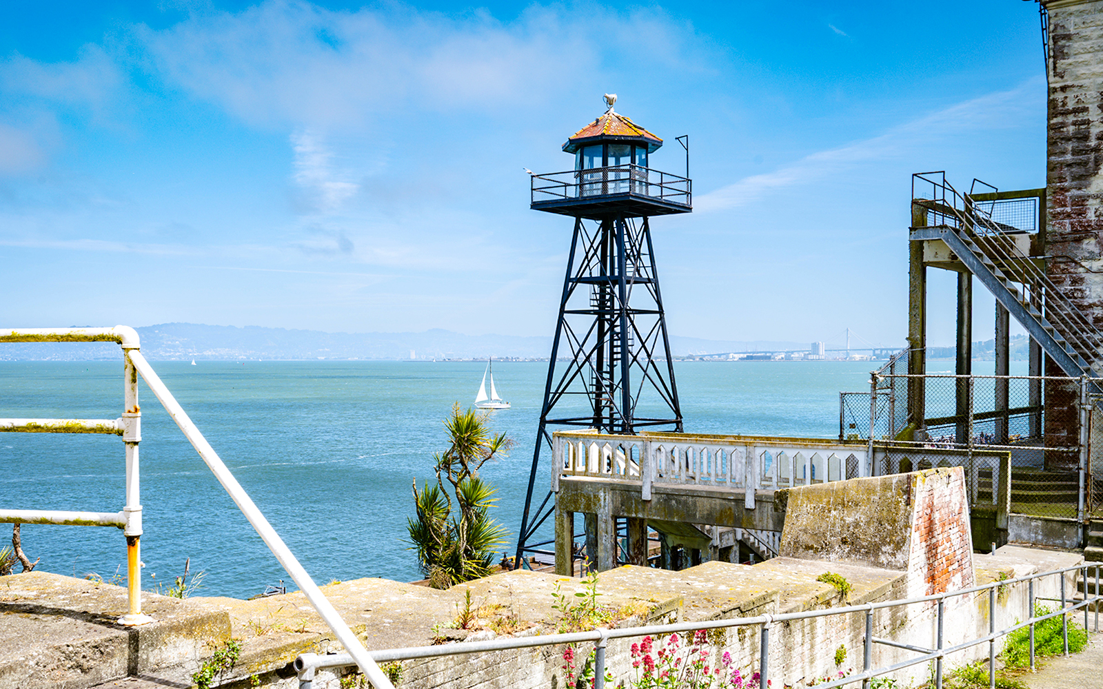 Historic guard tower on Alcatraz Island with steps and railing overlooking San Francisco Bay.