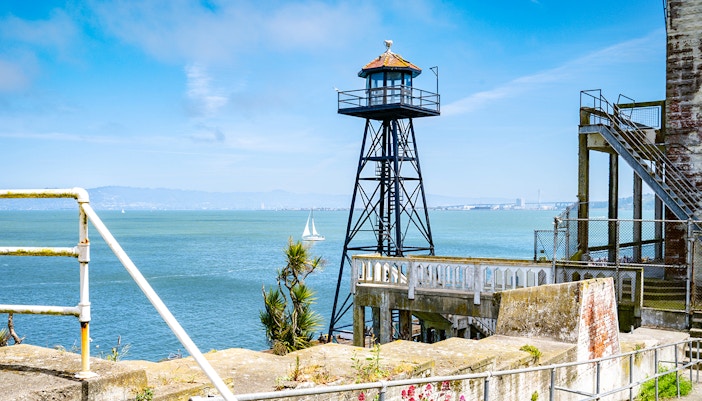 Historic guard tower on Alcatraz Island with steps and railing overlooking San Francisco Bay.
