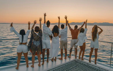 Tourists on a boat in Mallorca enjoying a sunset over the ocean.