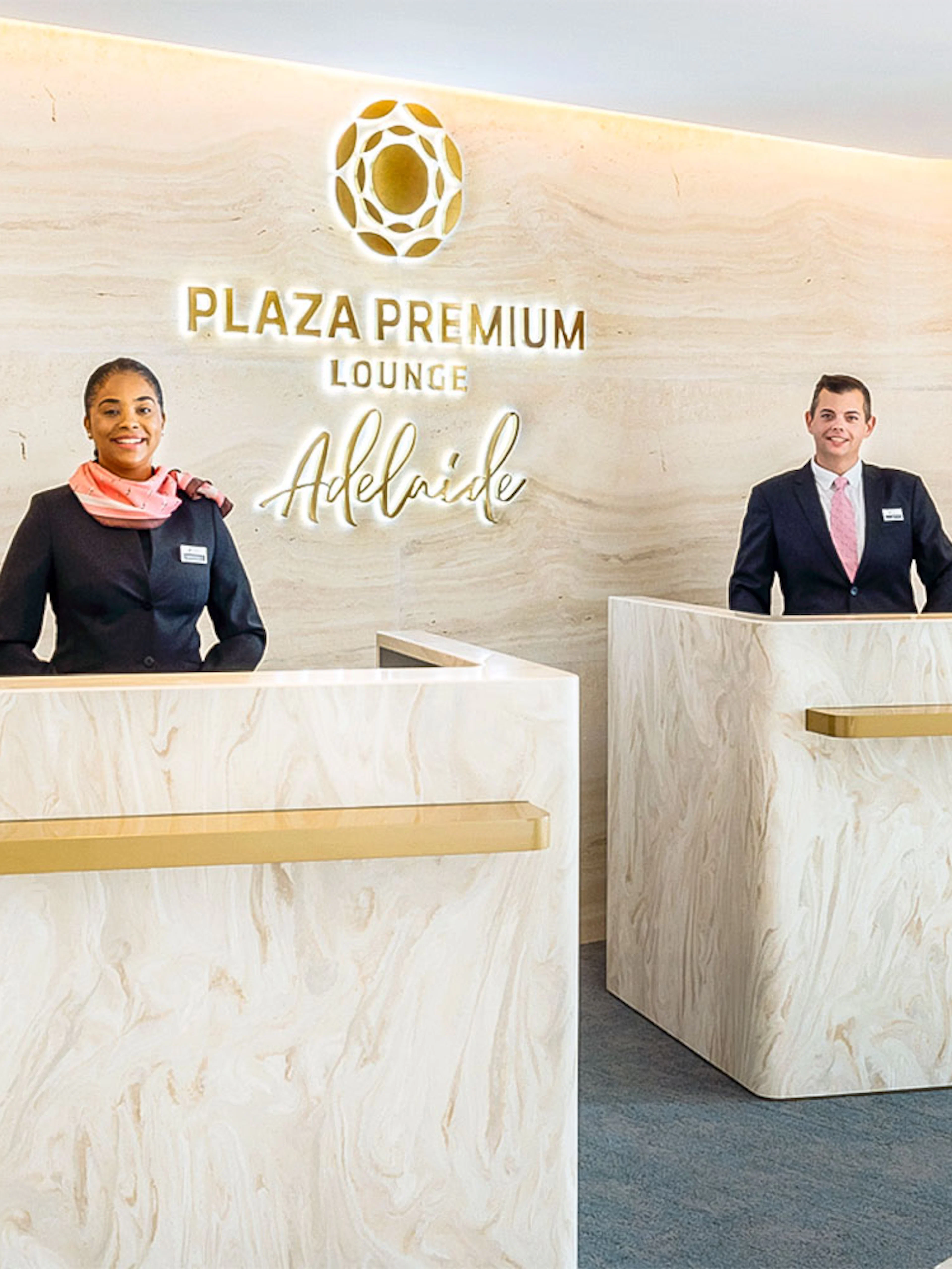 Reception area of Plaza Premium Lounge Adelaide with staff at marble desks.