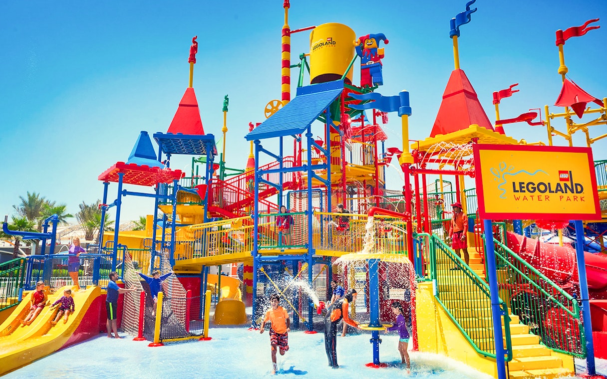 Families playing at LEGOLAND® Dubai Waterpark with colorful slides and water features.