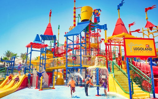 Families playing at LEGOLAND® Dubai Waterpark with colorful slides and water features.